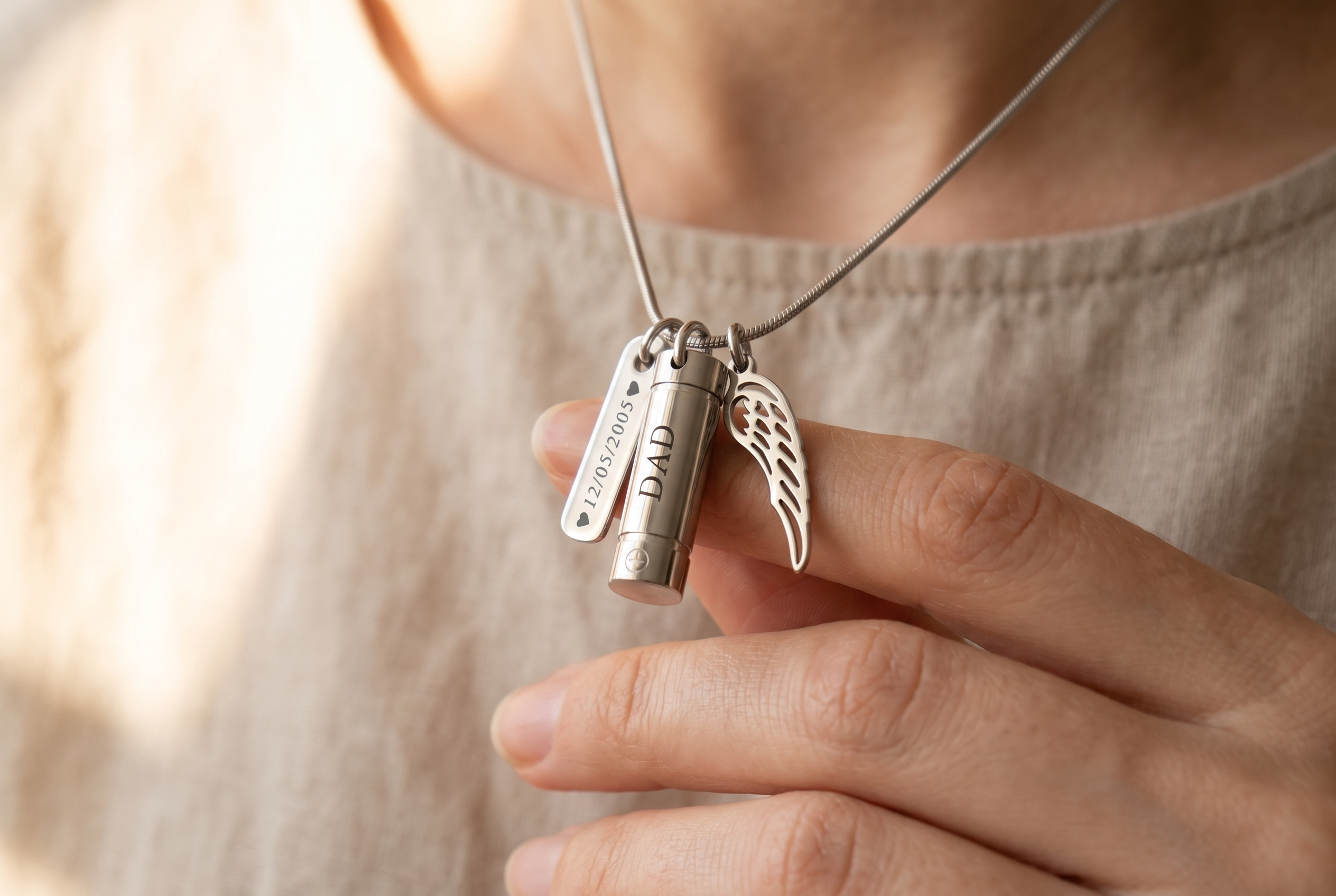 A hand gently holding an engraved memorial necklace close to the heart