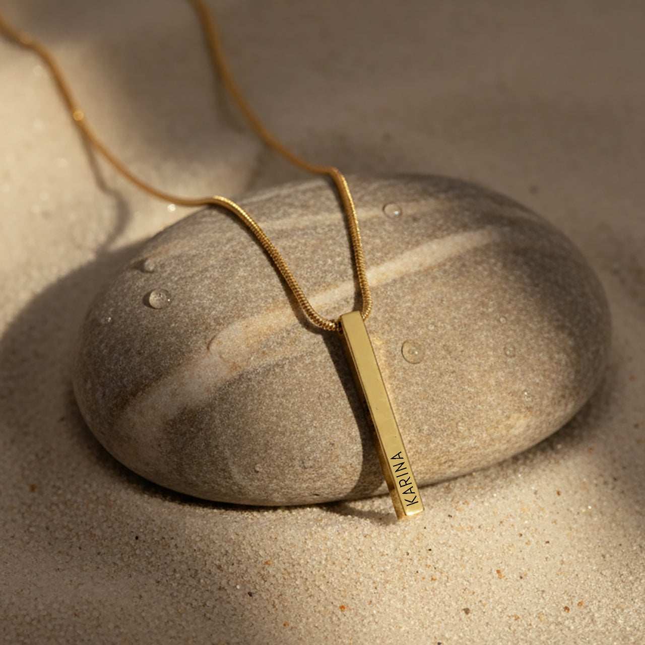 Bar Personalised Necklace by Belle Fever — gold vertical bar pendant resting on natural stone, a minimalist personalised necklace celebrating understated beauty and modern style.