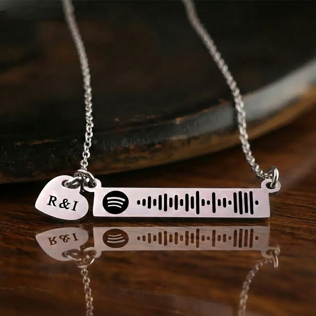 Personalized music bar necklace with engraved song code and heart charm displayed on a dark background, Belle Fever