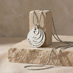Belle Fever Tower of Love necklace with multiple engraved disc charms, styled on a natural stone surface
