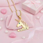Gold unicorn head necklace featuring birthstone detail and custom engraved name pendant.