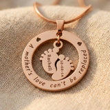 Close up of Can’t Be Replaced Necklace showing engraved message and baby feet charms detail design
