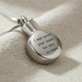 Close up of circle cremation necklace showing engraved message on round urn pendant