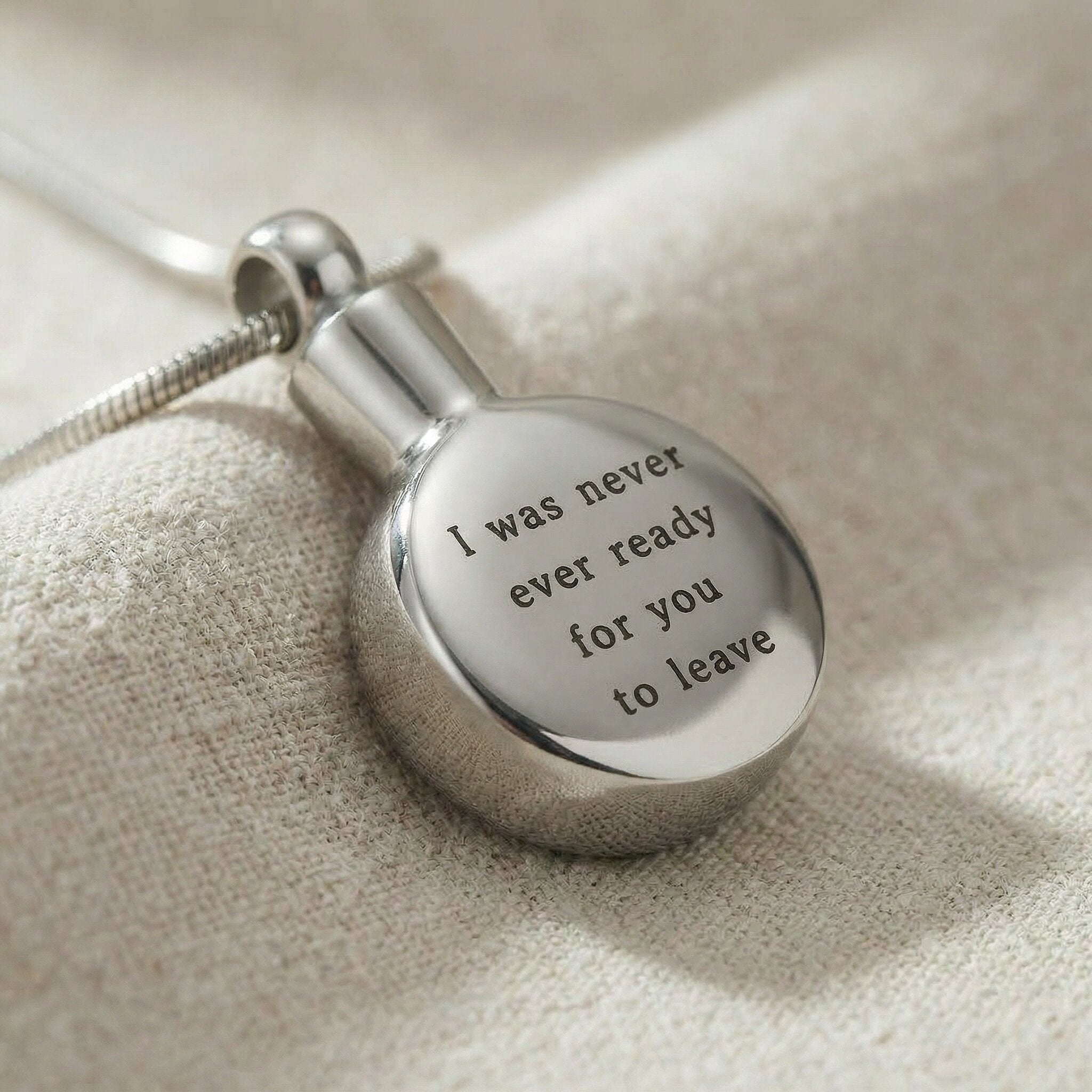 Close up of circle cremation necklace showing engraved message on round urn pendant