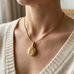 Woman wearing circle cremation necklace with round urn pendant on delicate chain