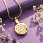 Belle Fever Circle Cremation Necklace in gold, engraved memorial pendant on soft purple background with dried flowers, personalised ashes keepsake jewellery, sympathy gift for loss remembrance.