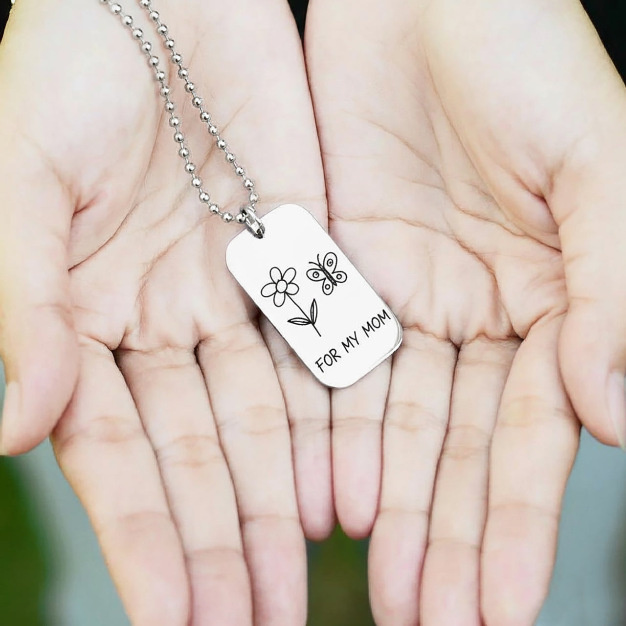 Belle Fever Custom Kids Drawing Dog Tag Necklace — engraved pendant resting in open hands, preserving a child’s drawing forever.