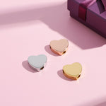Personalised Love Heart Charm – elegant gold, rose gold & silver heart-shaped beads displayed on soft pink background beside a gift box. A timeless Belle Fever keepsake symbolising love & connection.