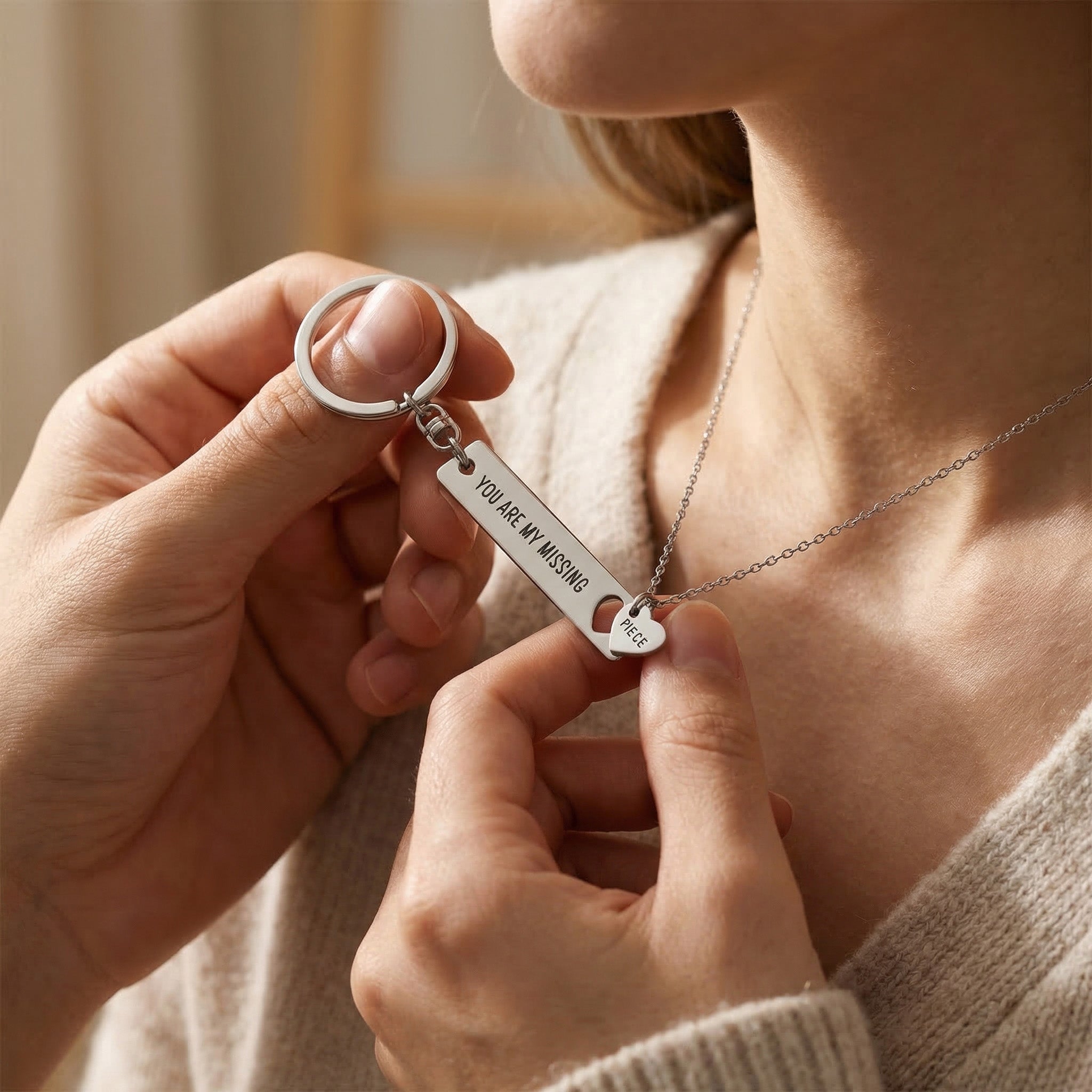 A woman wearing missing piece necklace while holding matching keyring, meaningful connection set