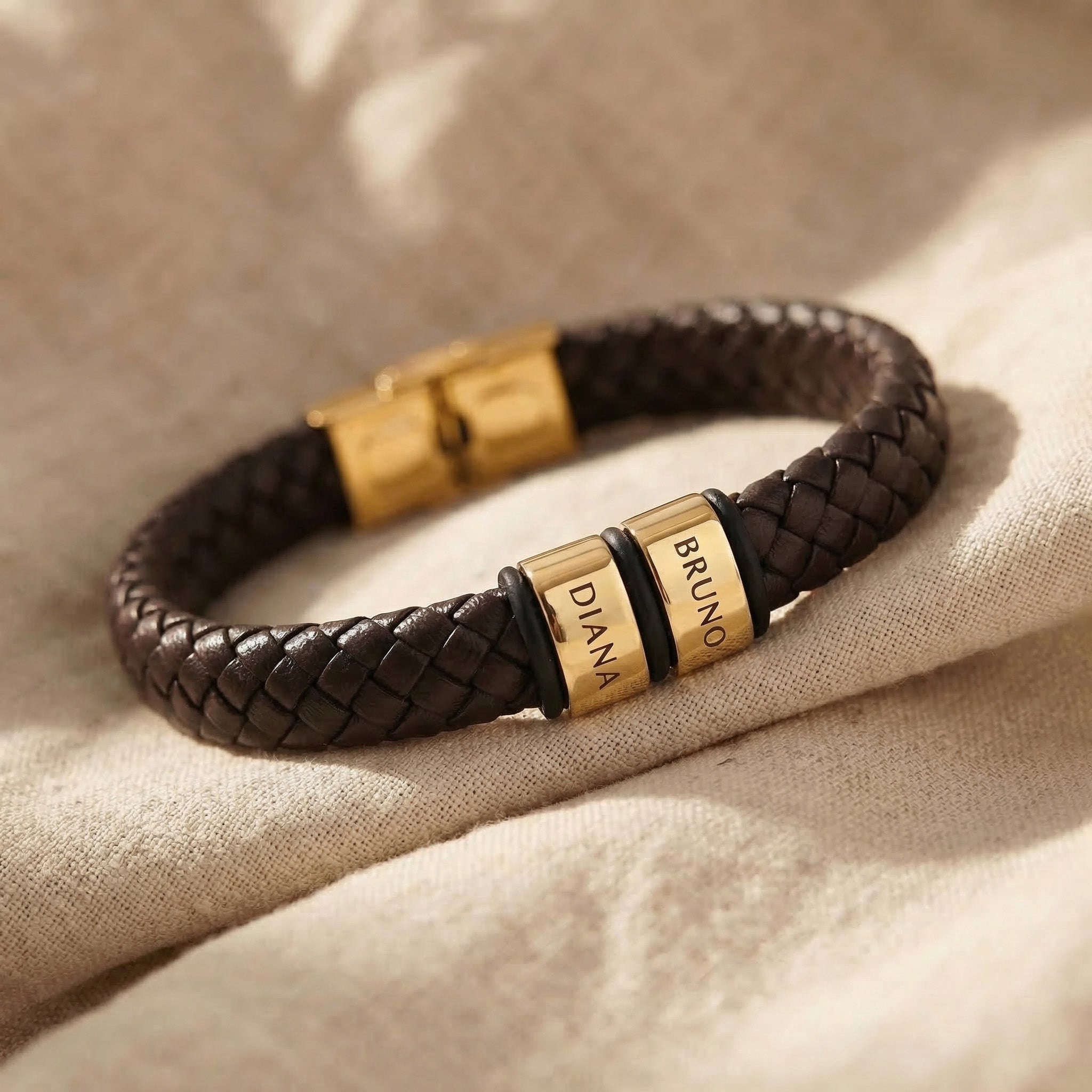 Personalised leather bracelet with gold engraved name charms, bold custom jewellery design