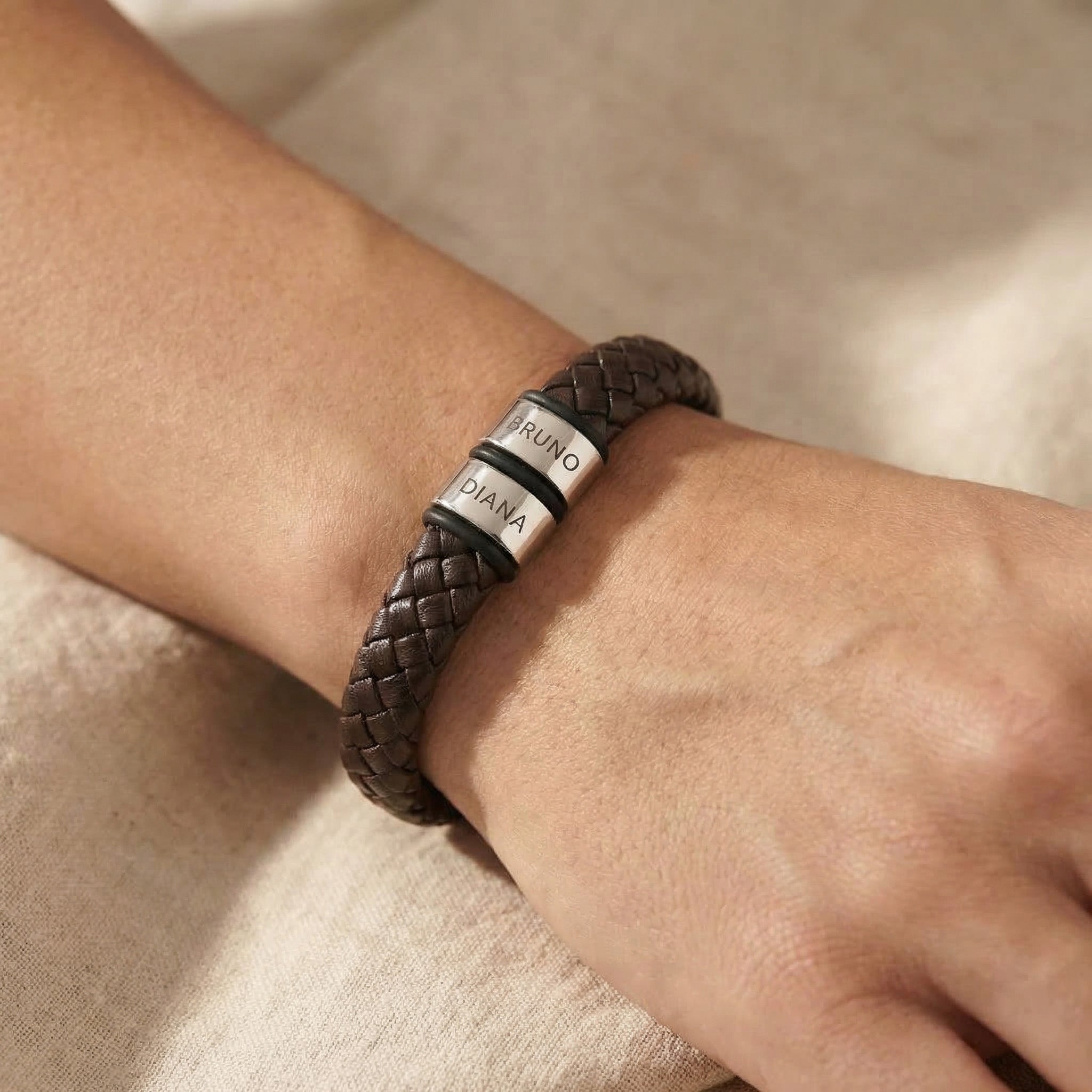 Man wearing personalised leather bracelet with engraved name charms, meaningful everyday accessory
