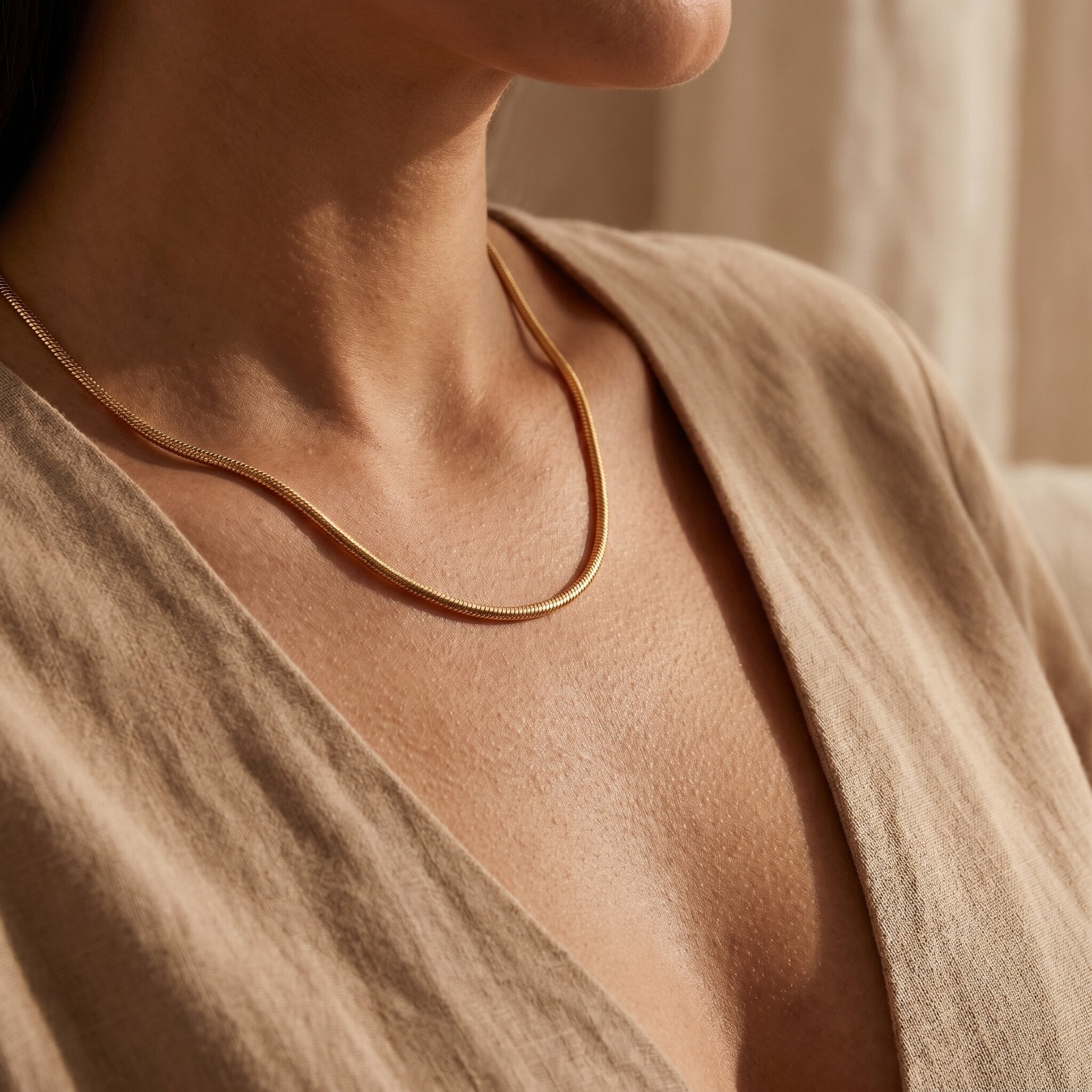 Woman wearing snake chain necklace, elegant minimalist chain jewellery for layering and modern styling