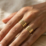 Hand wearing multiple personalised stackable rings with engraved names, layered style